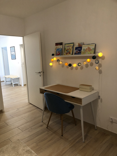 Bureau installé dans une chambre d’appartement de vacances, avec une chaise confortable et un espace de travail fonctionnel.